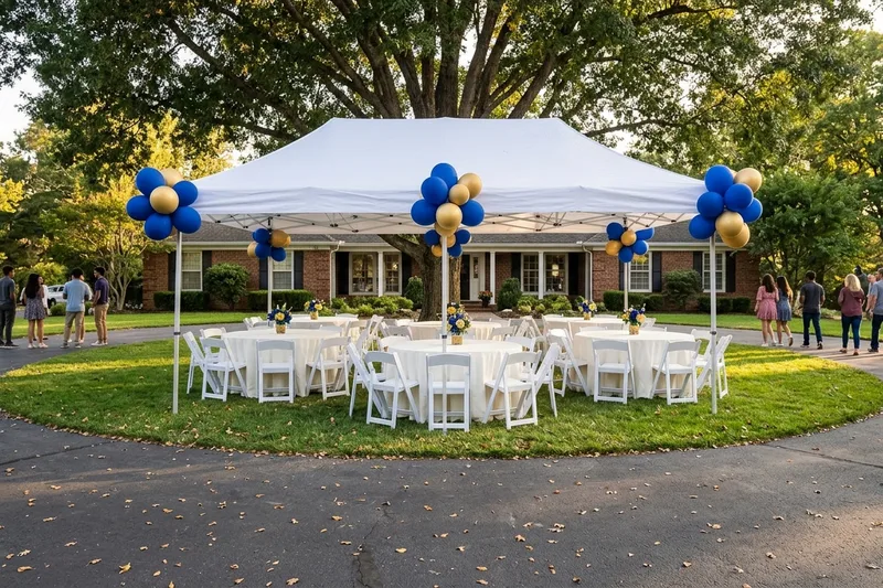 Graduation party in a front yard with round tables, white tablecloths and white resin padded chairs under a white canopy