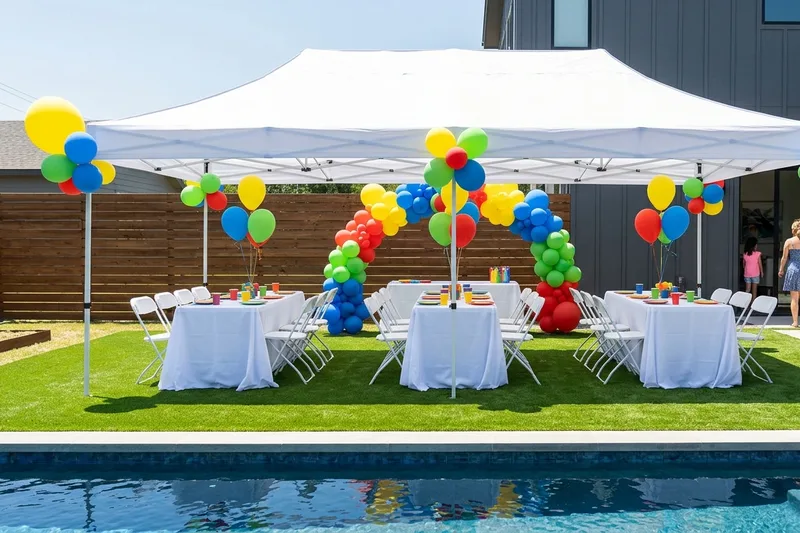 Kids birthday party by a pool with rectangle tables in white tablecloths and white folding chairs under a white canopy